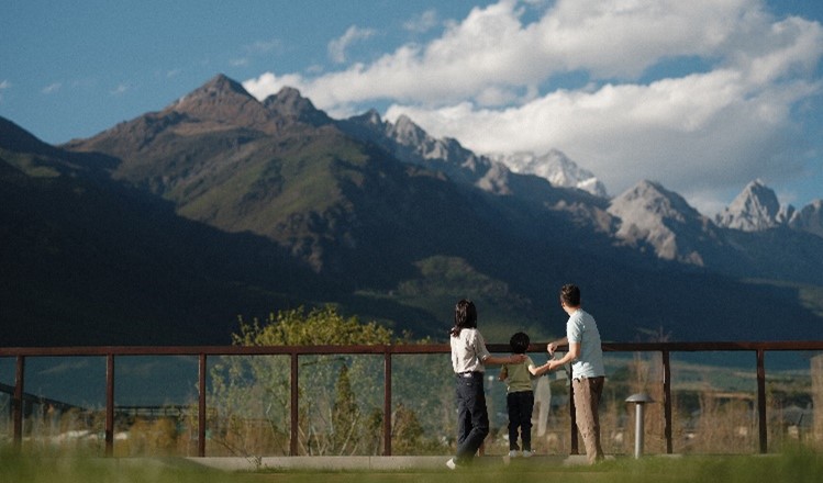 A group of people standing on a fence in front of a mountainDescription automatically generated with low confidence